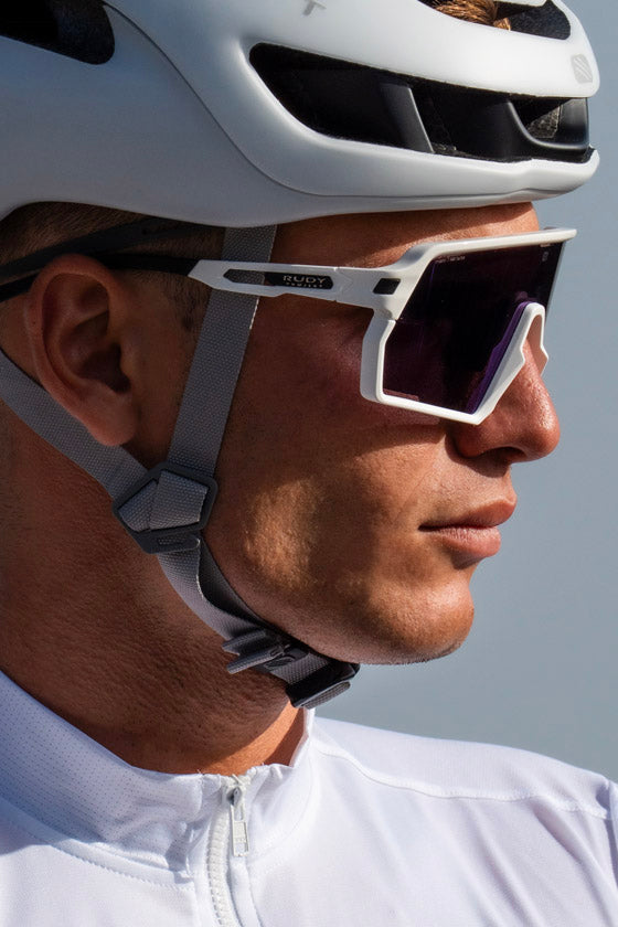 Person wearing a white helmet and sunglasses with a neutral background